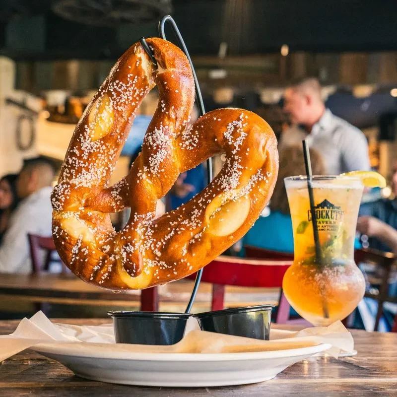 Salted pretzel, sauces, and Crockett Tavern San Antonio drink.