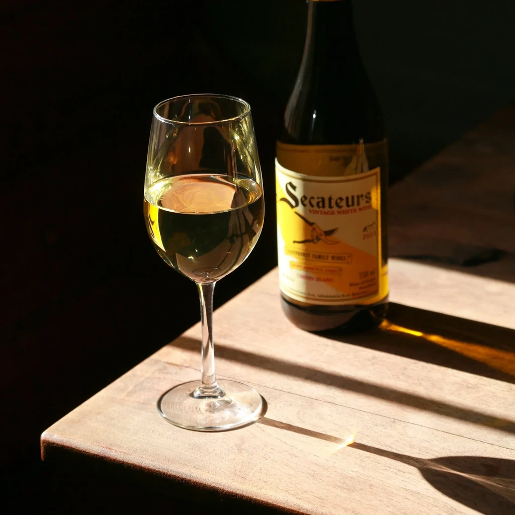 Glass of white wine and Secateurs vintage bottle on wood.