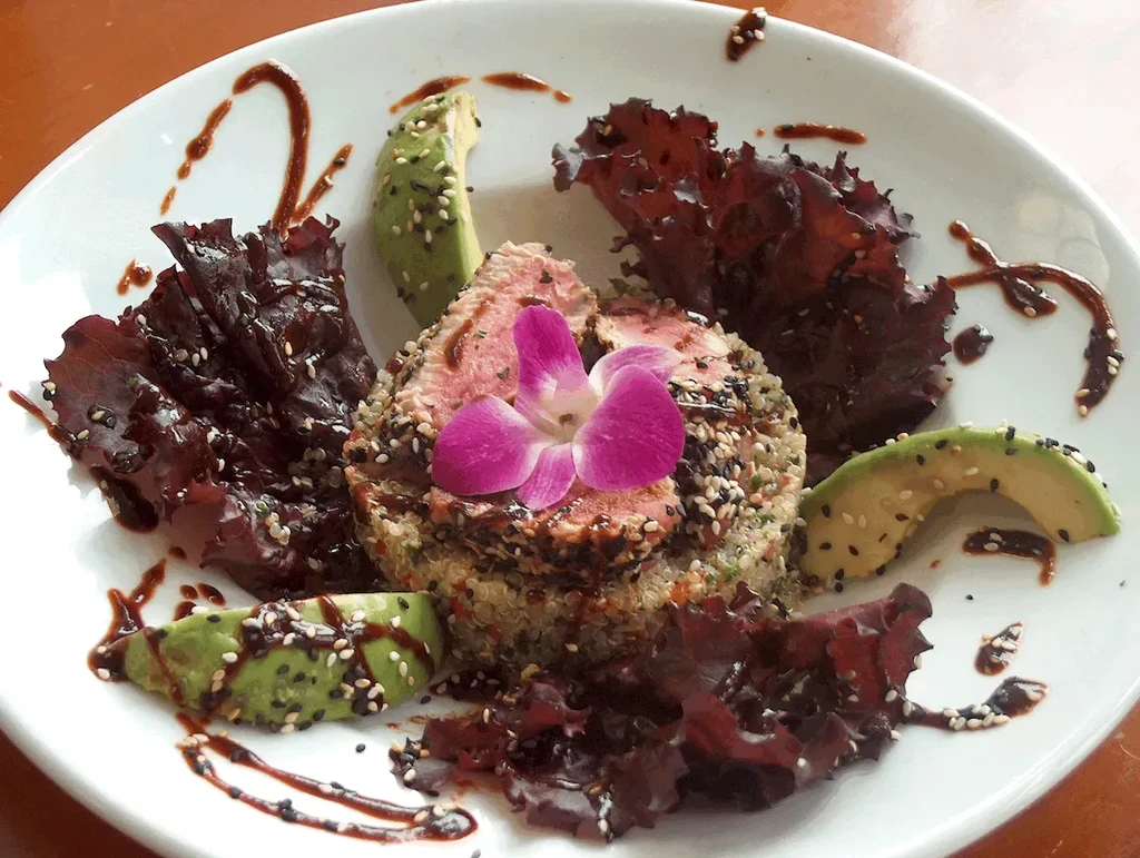 Pan-seared sesame tuna, quinoa, avocado, greens, with orchid and glaze.