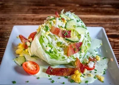 Close-up of a wedge salad with bacon, egg, chives, and dressing.