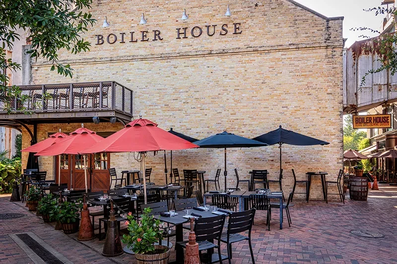BOILER HOUSE restaurant exterior: outdoor dining with red and dark umbrellas.