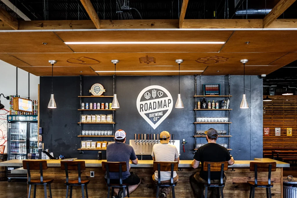 Roadmap Brewing Co. modern bar with logo, drinks, and customers.