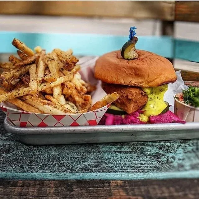 Brioche burger, seasoned fries, and side on rustic wooden table.