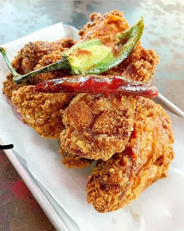 Crispy fried chicken garnished with green and red chili peppers.