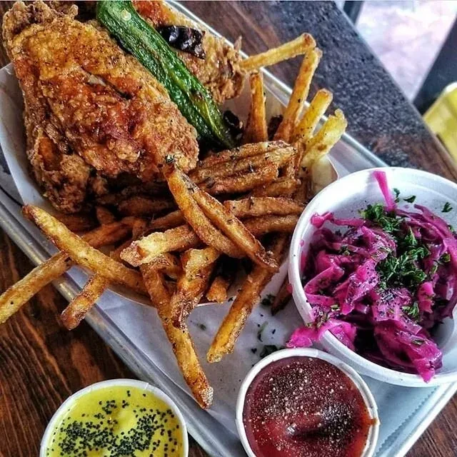 Fried chicken, fries, green vegetable, coleslaw, and sauces on a tray.