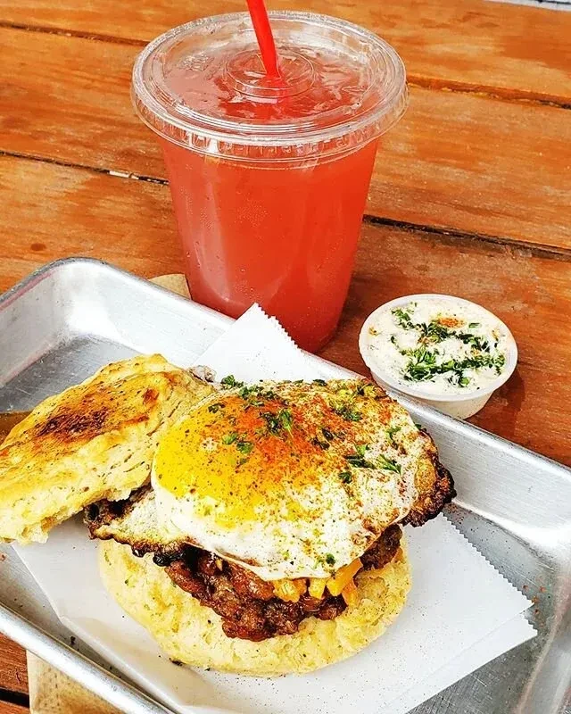 Close-up: Seasoned split biscuit sandwich with sausage, egg, and cheese.