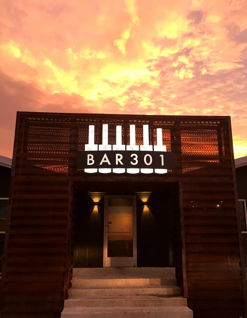 Modern BAR 301 entrance glows under a dramatic sunset sky.