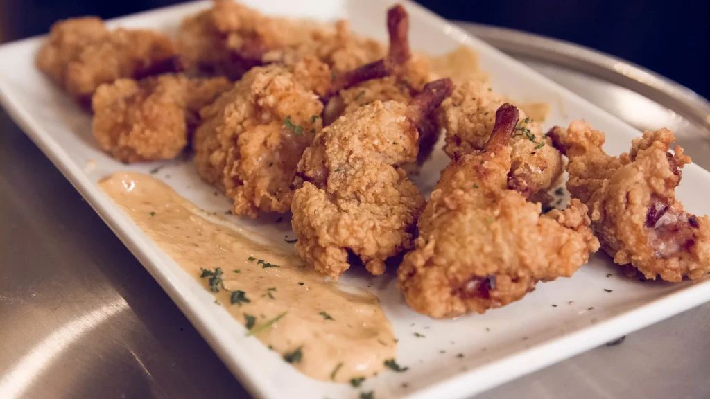 Crispy fried shrimp or chicken lollipops with herb-garnished sauce.