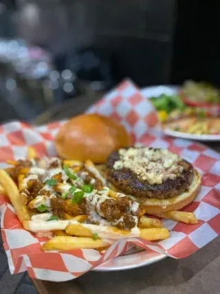 Close-up of burger and chili cheese fries in a checkered paper-lined basket.