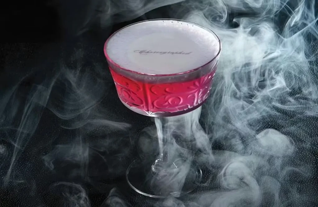 Magenta cocktail in cut glass, 'Absolutley Fabulous' on foam, smoky background.