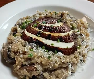 Close-up of creamy mushroom risotto with sliced mushroom cap, cheese, and herbs.