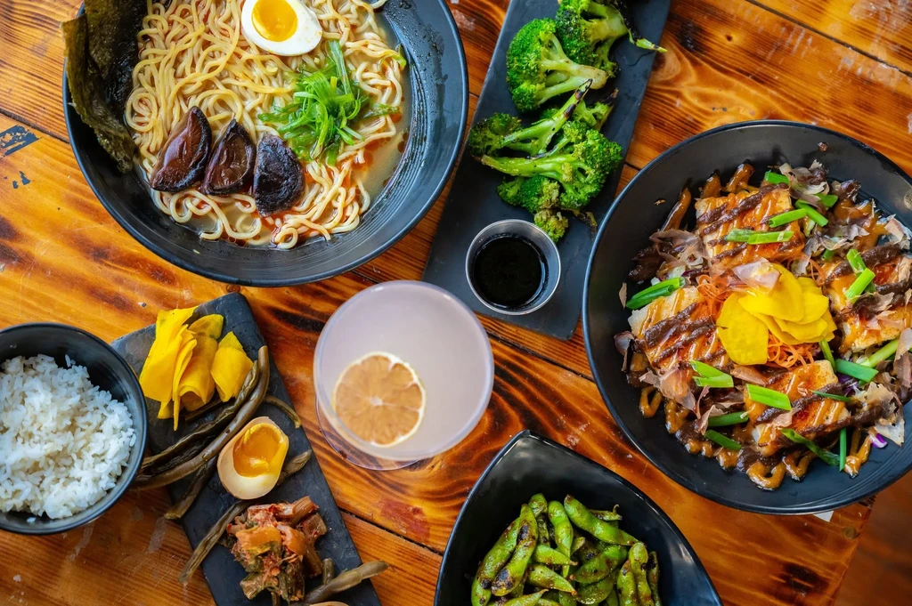 Top-down view of various Asian dishes on a rustic wooden table.