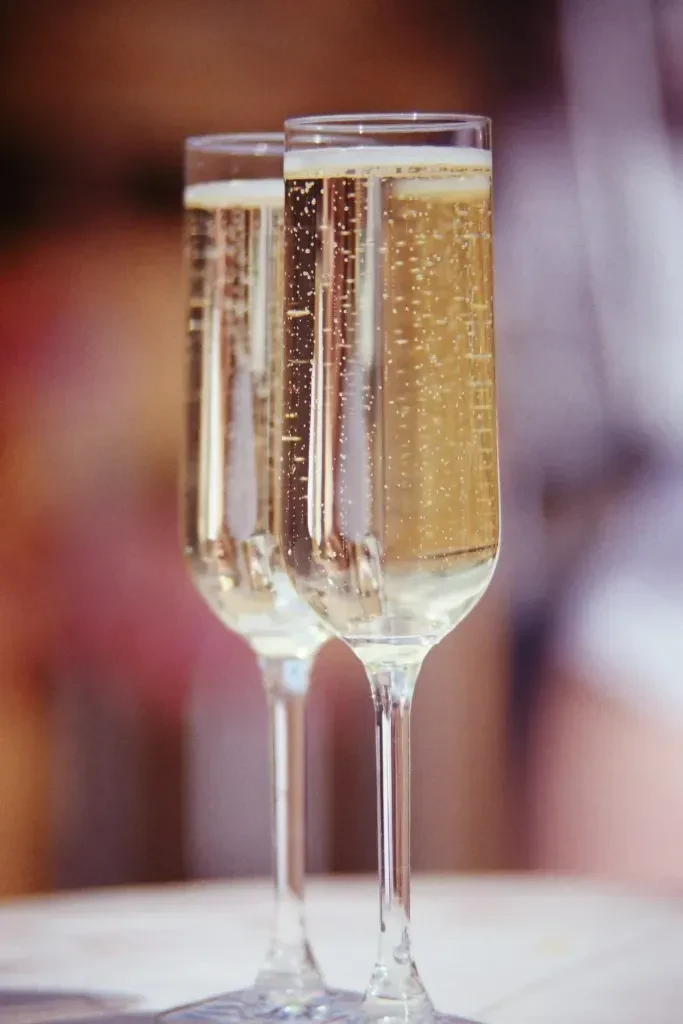 Two champagne flutes filled with effervescent golden liquid, blurred background.