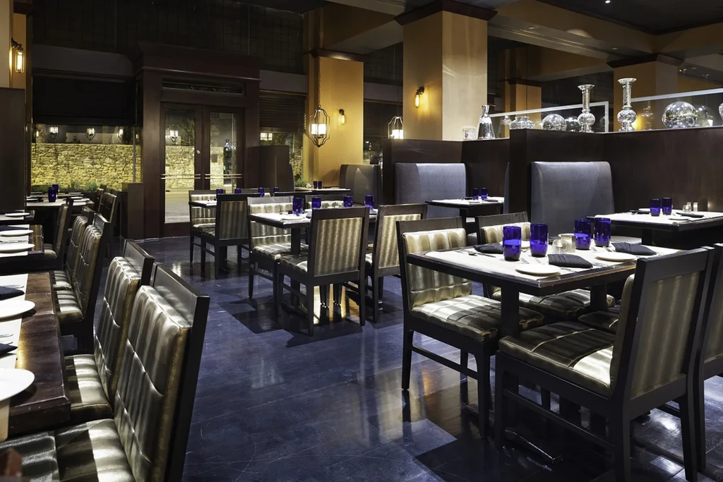 Elegant, modern restaurant interior with set tables and cobalt blue glasses.
