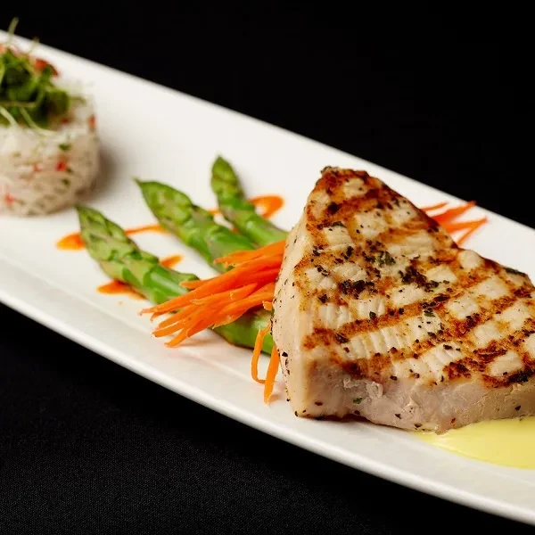 Meticulously plated grilled fish with asparagus, carrots, and rice.