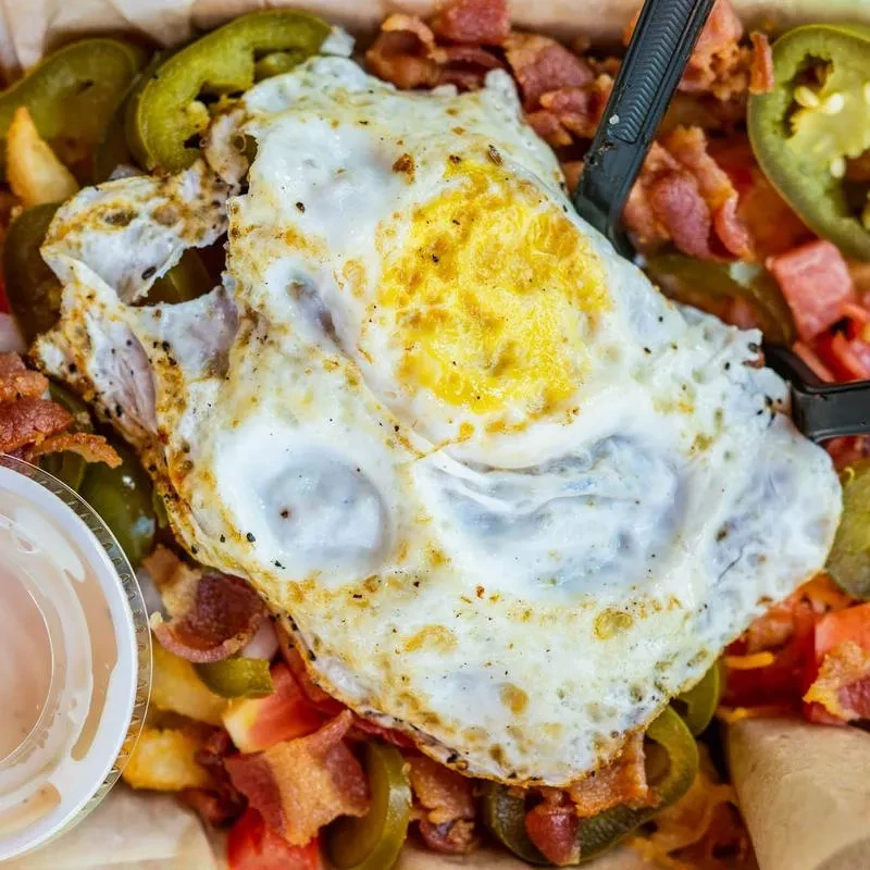 Fried egg with runny yolk, bacon, jalapeños, and potatoes.