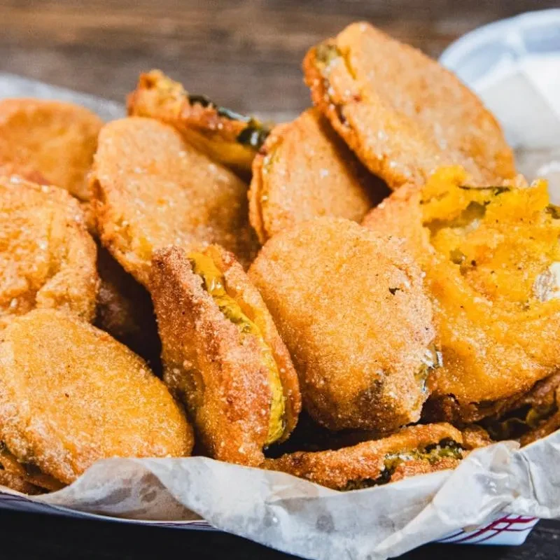 Close-up of golden-brown fried pickles or green tomatoes in a basket.