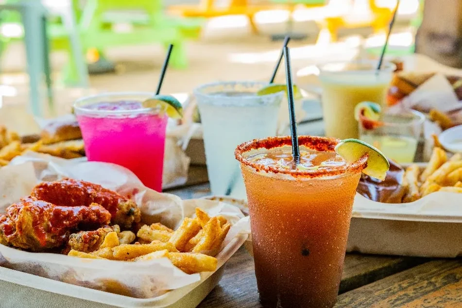 Platter of chicken wings, fries, and a chili-rimmed drink outdoors.