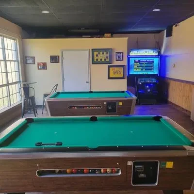 Casual game room with two pool tables and arcade machines.