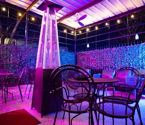 Empty restaurant patio at night with purple and blue LED lighting.