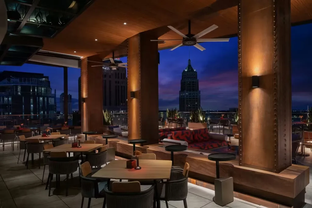 Sophisticated rooftop bar at dusk, modern seating, city skyscraper view.
