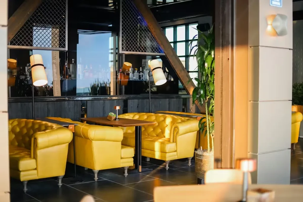 Interior of a modern restaurant with yellow Chesterfield sofas and industrial architecture.