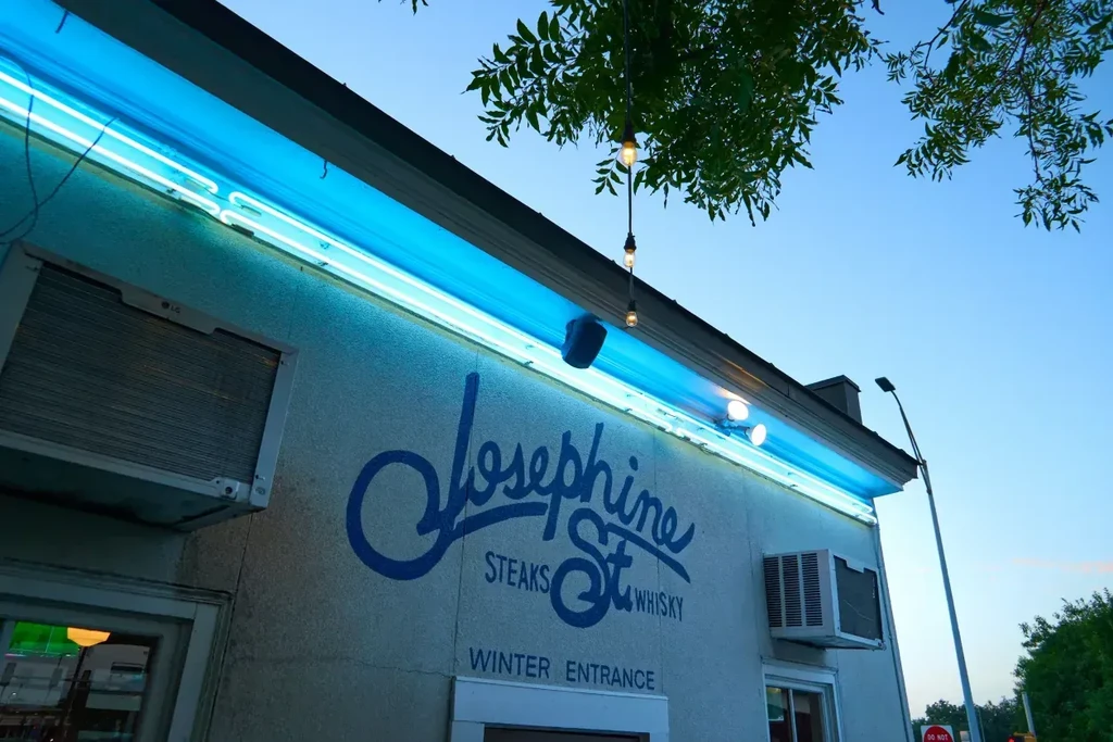 Exterior of 'Josephine St Steaks & Whisky' with blue neon and string lights.