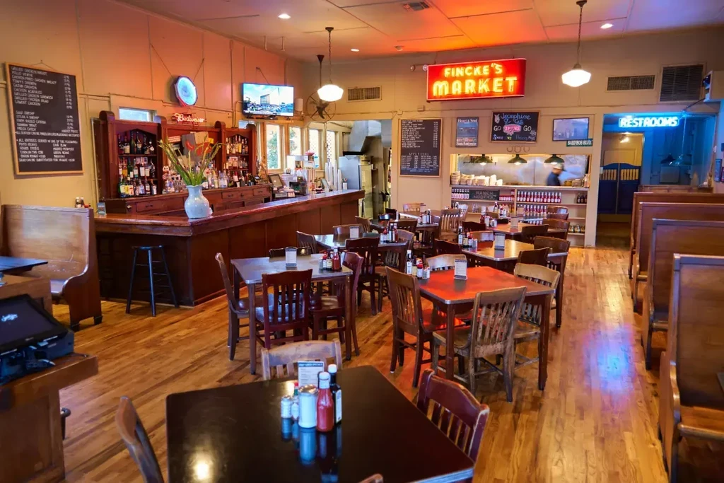 Warmly lit Fincke's Market restaurant interior with wooden tables and bar.