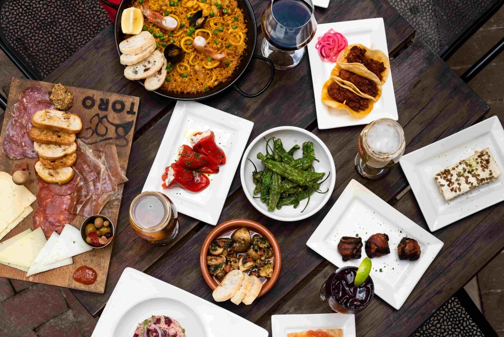 Paella, charcuterie, and various tapas dishes with drinks on a table.