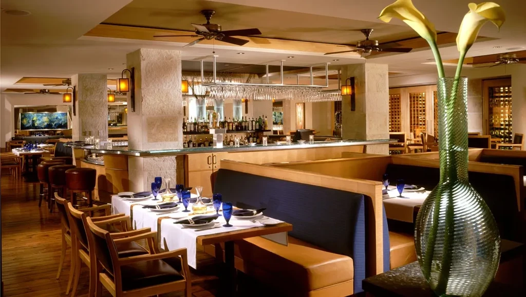 Warm, upscale restaurant interior featuring dining tables and a prominent bar.