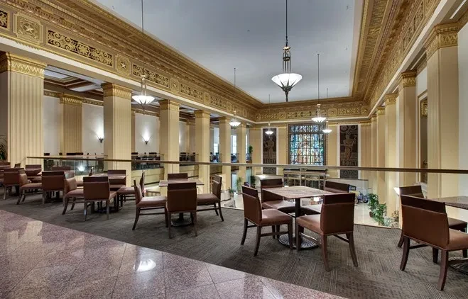 Ornate, empty dining room with columns, gold ceiling, and stained glass.