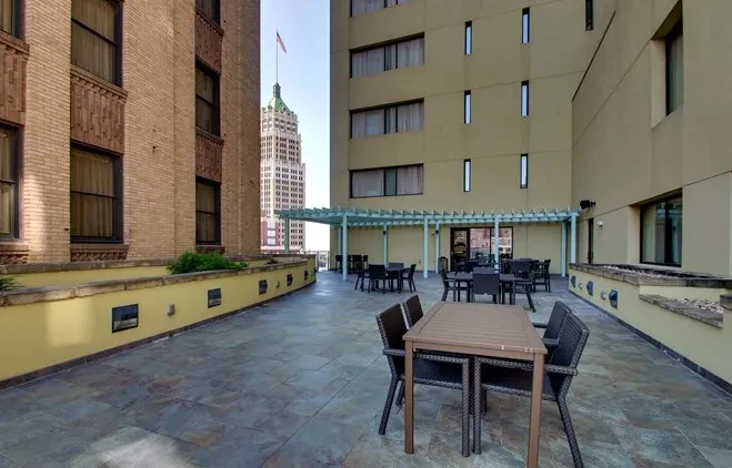 Empty urban outdoor dining patio with tables, chairs, and pergola.
