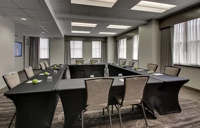 Empty U-shaped professional meeting room with apples, water, and notepads.