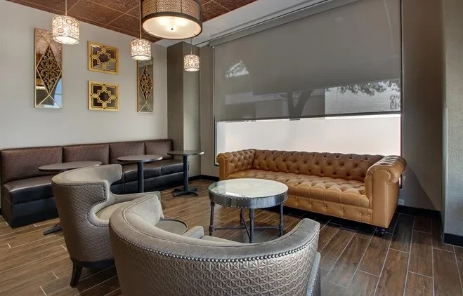 Lounge with banquette, Chesterfield sofa, armchairs, and decorative ceiling.
