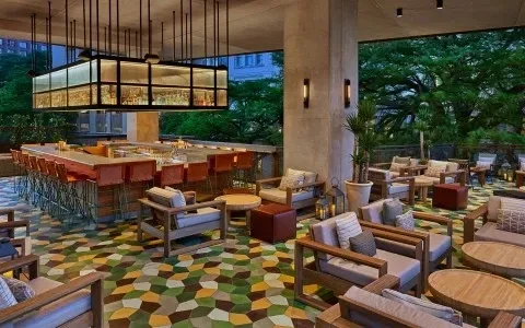 Modern outdoor bar and lounge with geometric floor and illuminated liquor display.