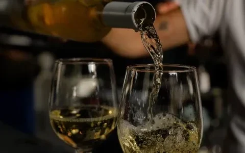 Close-up of white wine pouring from bottle into a wine glass.