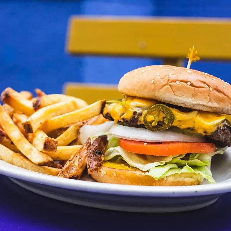 A cheeseburger with melted cheese, jalapeños, and french fries.
