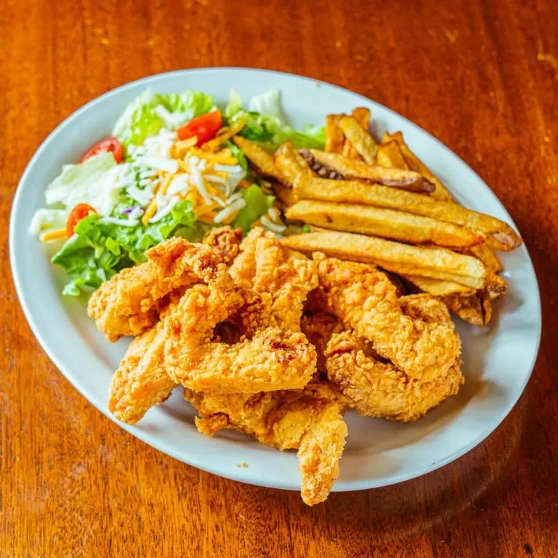 Plate of golden-brown fried chicken/shrimp, french fries, and salad.