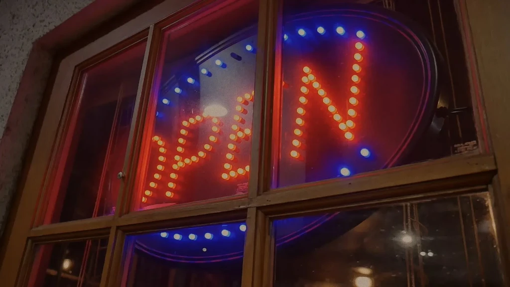 Red LED OPEN sign with blue border through a window at night.
