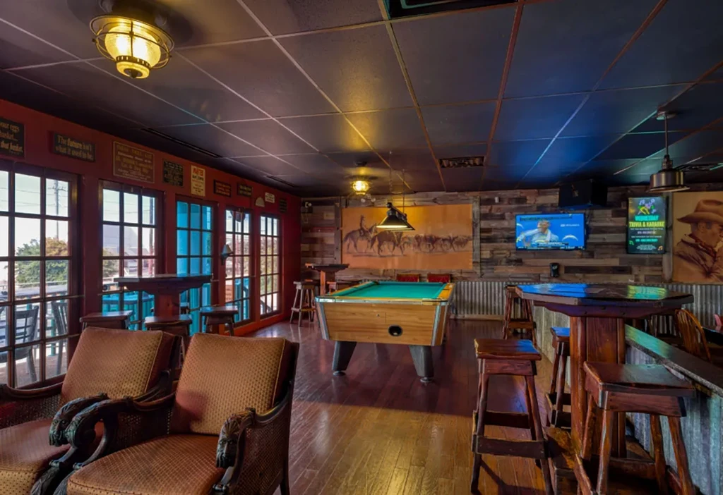 Western-themed bar interior with a pool table and desert camel mural.