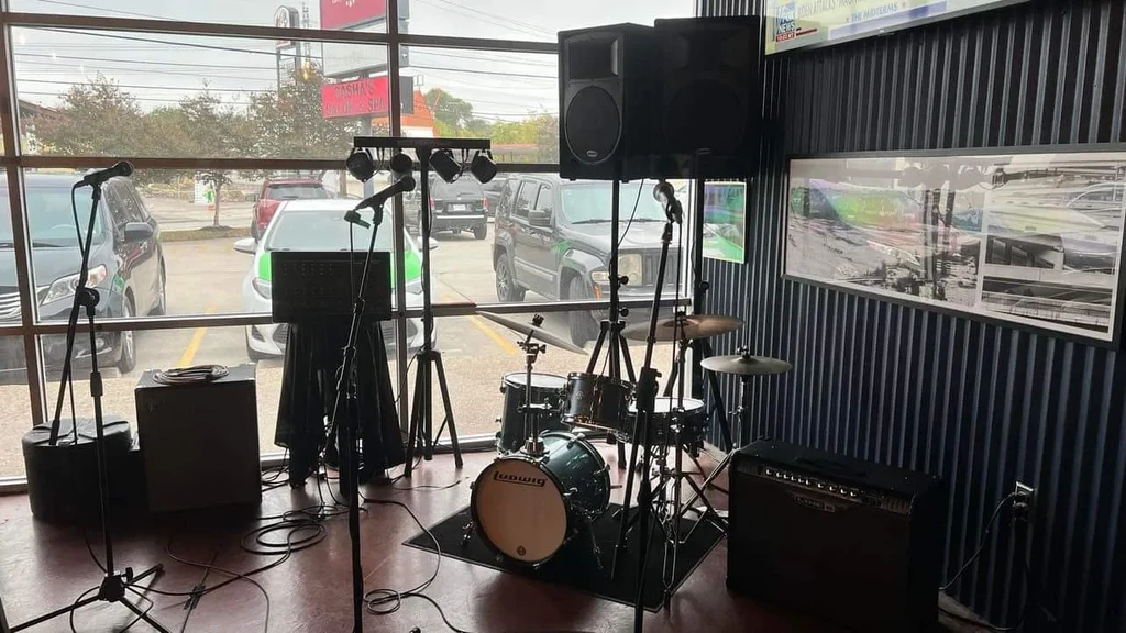 Stage setup with Ludwig drums, speakers, and mics by storefront windows.
