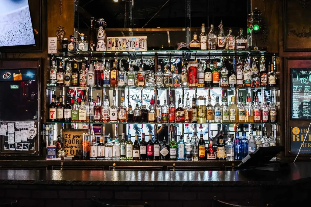 Well-stocked bar with brightly lit shelves of liquor bottles.