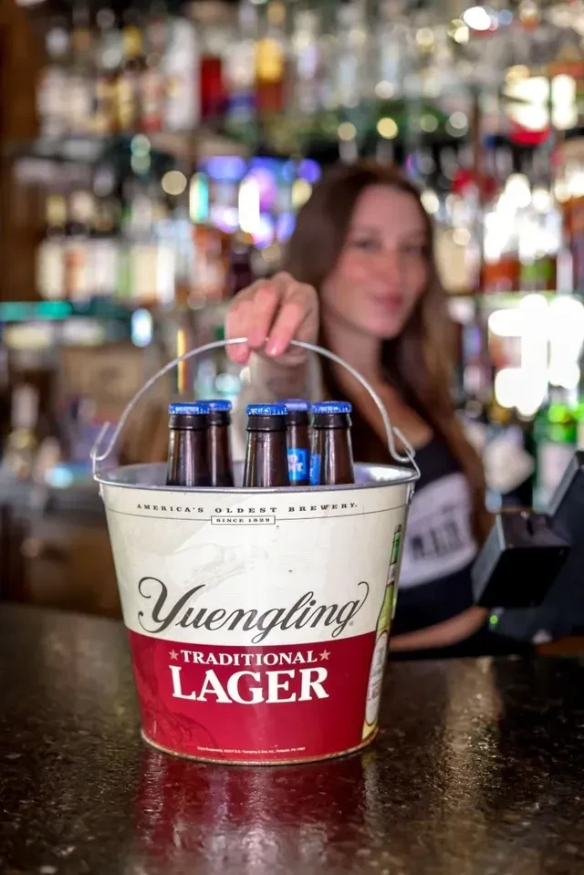 Yuengling Traditional Lager bucket with ice and bottles on a bar.
