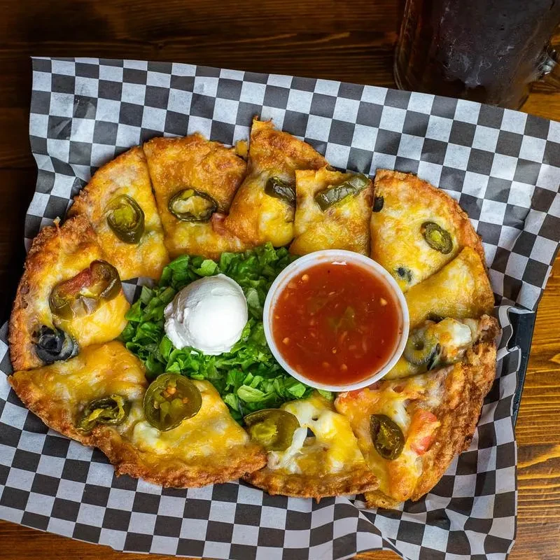 Cheesy nachos with jalapeños, salsa, and sour cream in a basket.