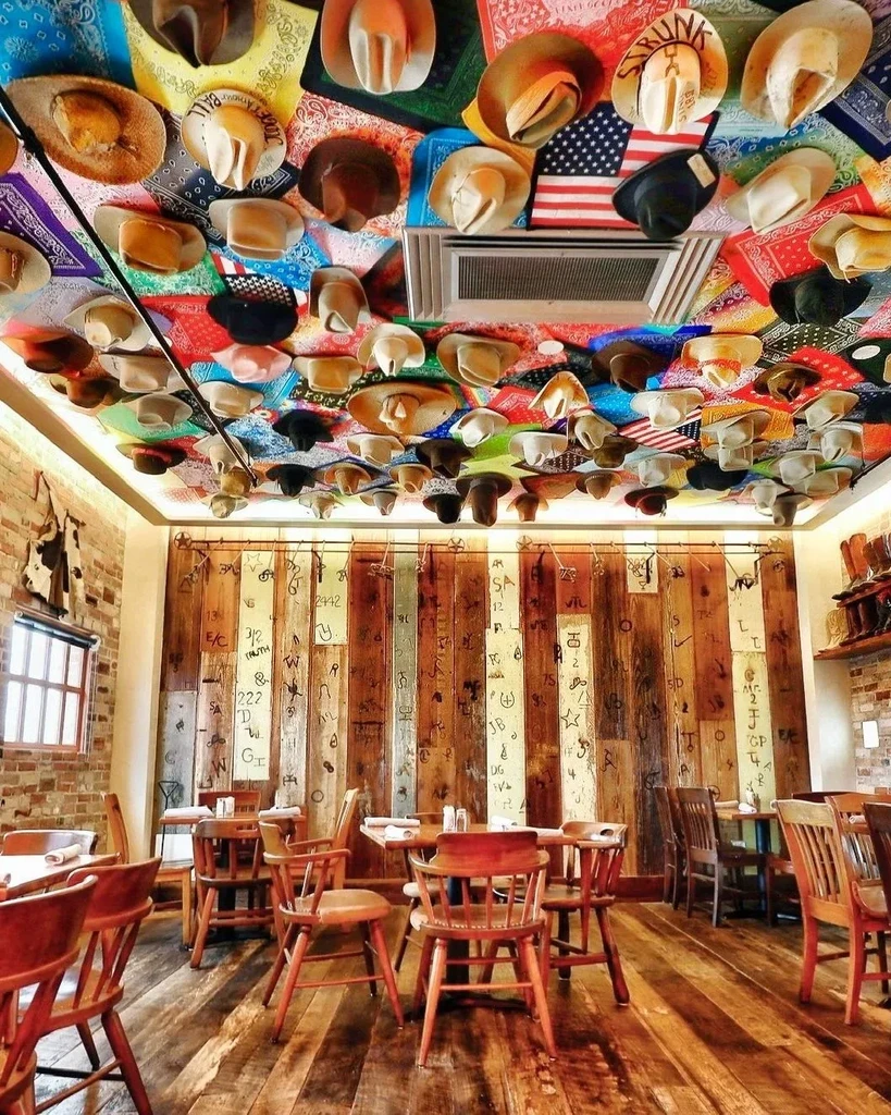 Western restaurant interior: ceiling of hats and bandanas, branded walls.