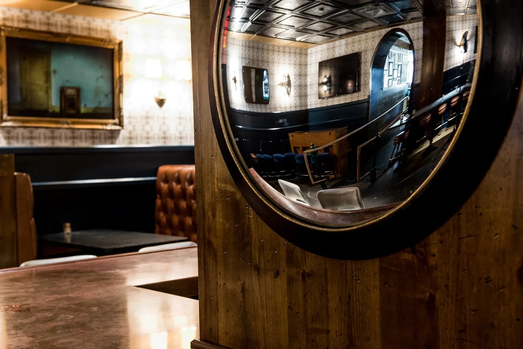 Large circular convex mirror reflecting a warm restaurant bar interior.