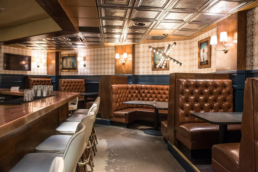 Bar interior with copper counter, embossed tin ceiling, leather booths.