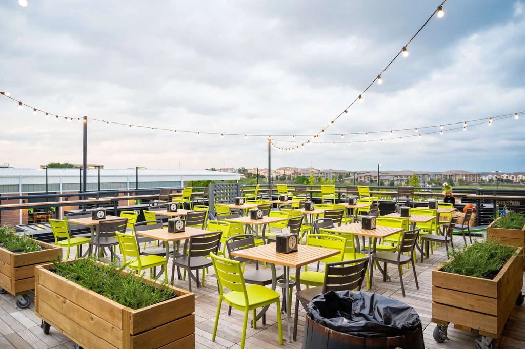 Rooftop deck with lime green and grey dining furniture under string lights.