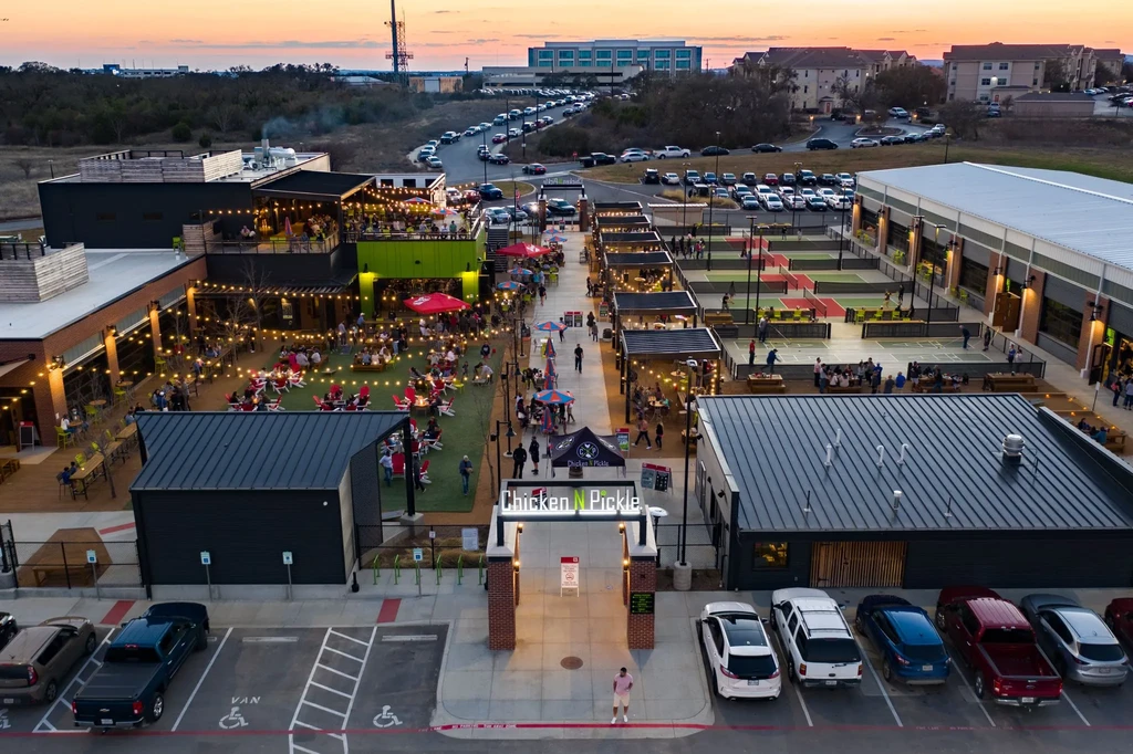 Bustling aerial view of Chicken N Pickle outdoor pickleball and dining complex.