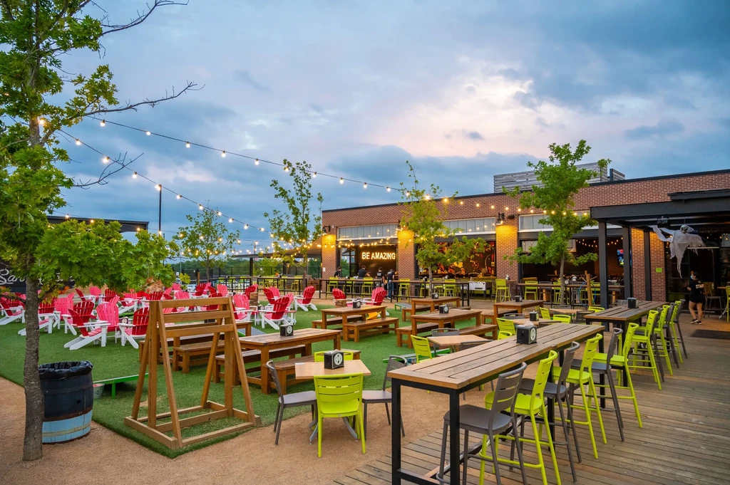 Outdoor restaurant area at dusk with string lights and multiple seating types.